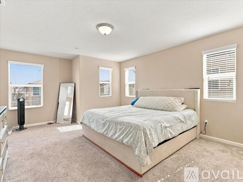 A bedroom with a large bed and a window with blinds.