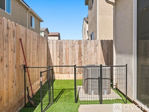 A backyard with a wooden fence, a green lawn, and a playground.