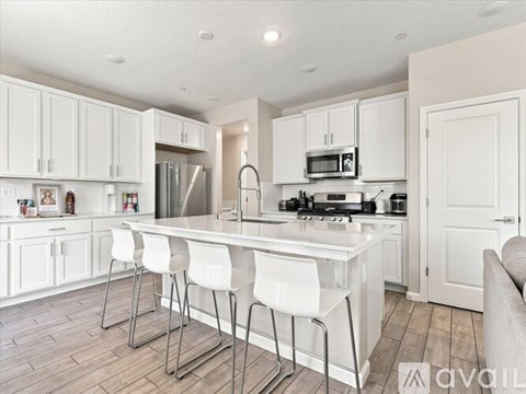 A kitchen with white cabinets and a white island with four chairs.