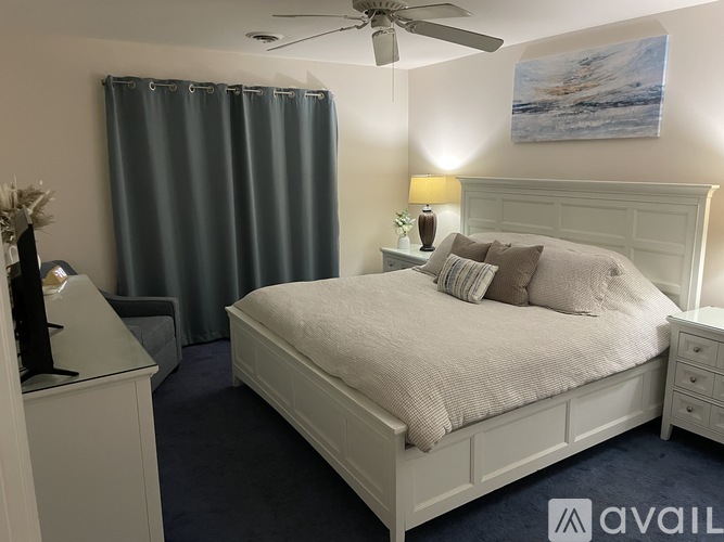 A bedroom with a bed, nightstand, and a painting on the wall.