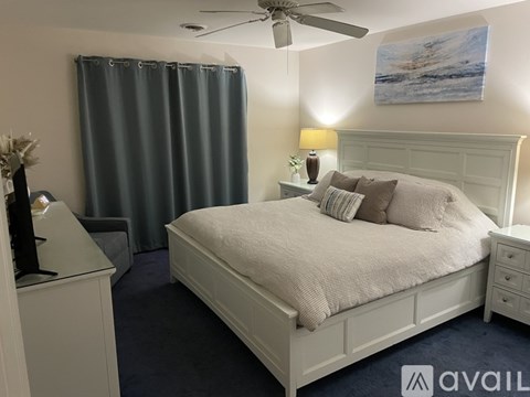 A bedroom with a bed, nightstand, and a painting on the wall.