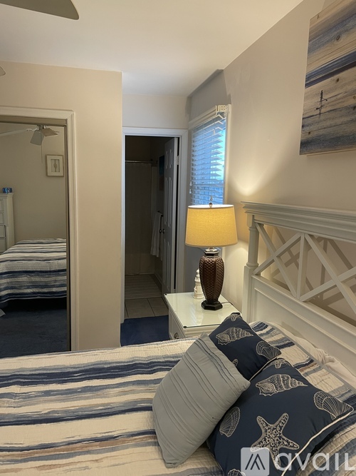 A bedroom with a bed, a lamp, and a painting on the wall.