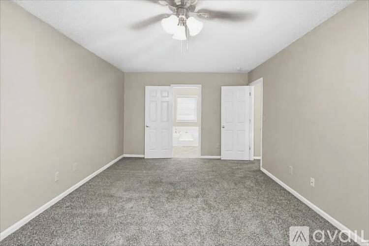 A room with a ceiling fan and two doors.