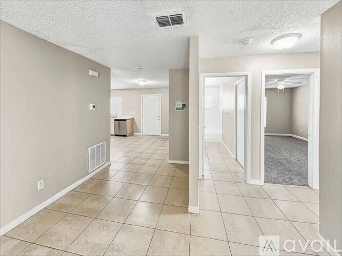 A spacious room with tiled flooring and a few doors.