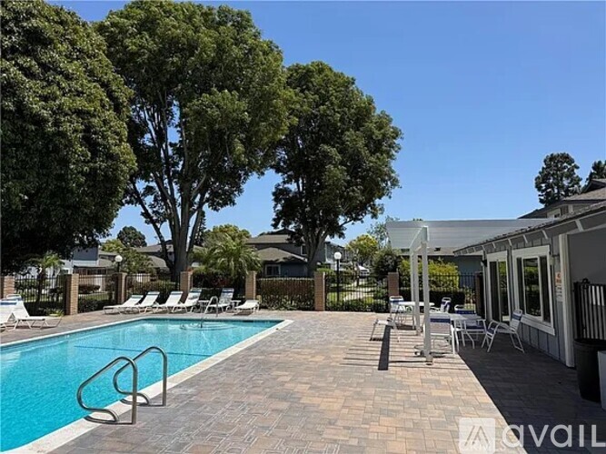 A pool surrounded by trees and chairs.