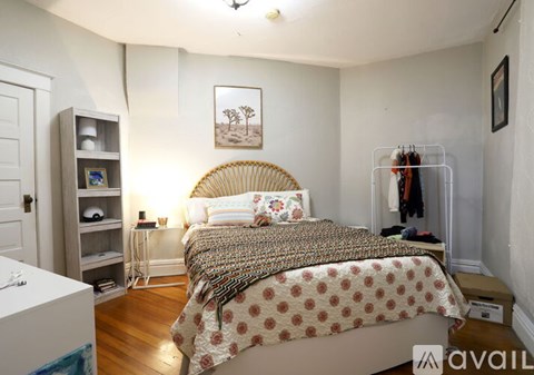 A bedroom with a bed, a nightstand, a lamp, a shelf, and a picture on the wall.