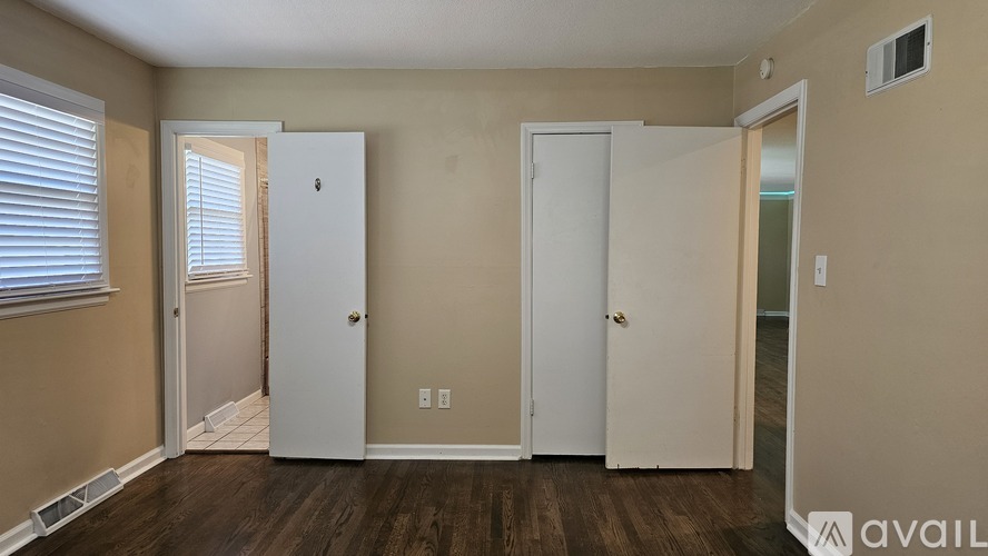 Three white doors in a room with wooden floors and beige walls.