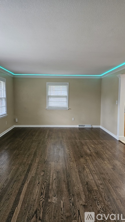 A room with wooden flooring and a window with blinds.