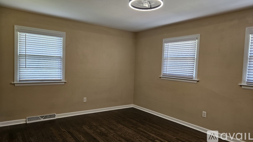 A room with two windows and a wooden floor.