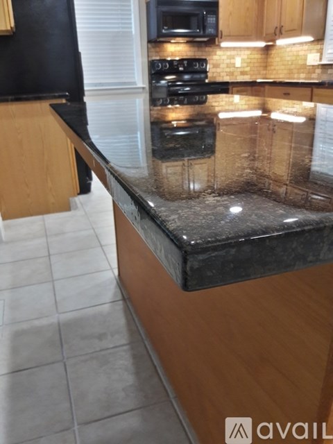 A kitchen with a black counter top and wooden cabinets.