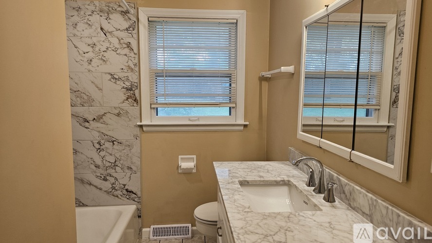 A bathroom with a marble countertop and a window with blinds.