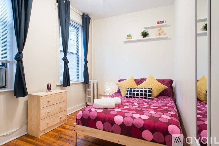 A bedroom with a bed, nightstand, and window with curtains.