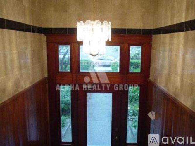 A hallway with a chandelier and a sign that says "Alpha Realty Group".