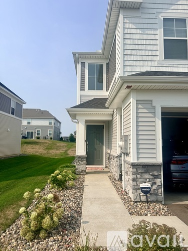 A house with a grey siding and a white roof with a stone pathway leading to the front door.