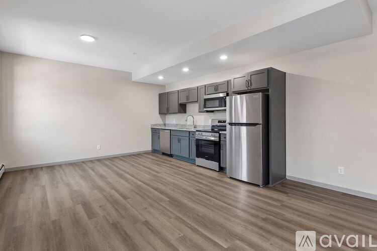 A kitchen with stainless steel appliances and wooden flooring.
