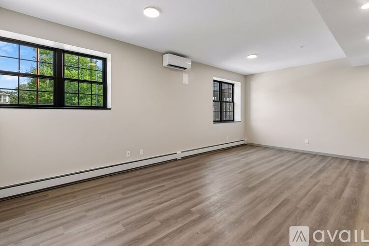 A spacious room with wooden flooring and a window with black frames.
