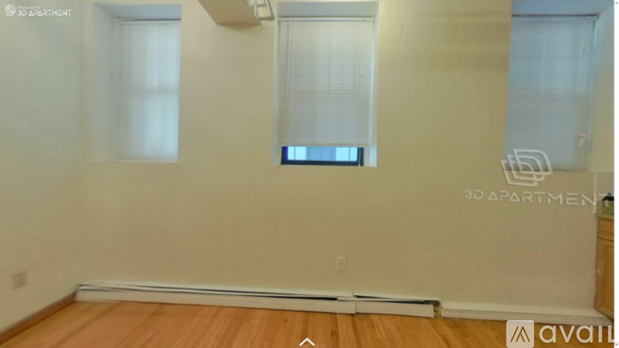 A room with wooden flooring and a window with blinds.