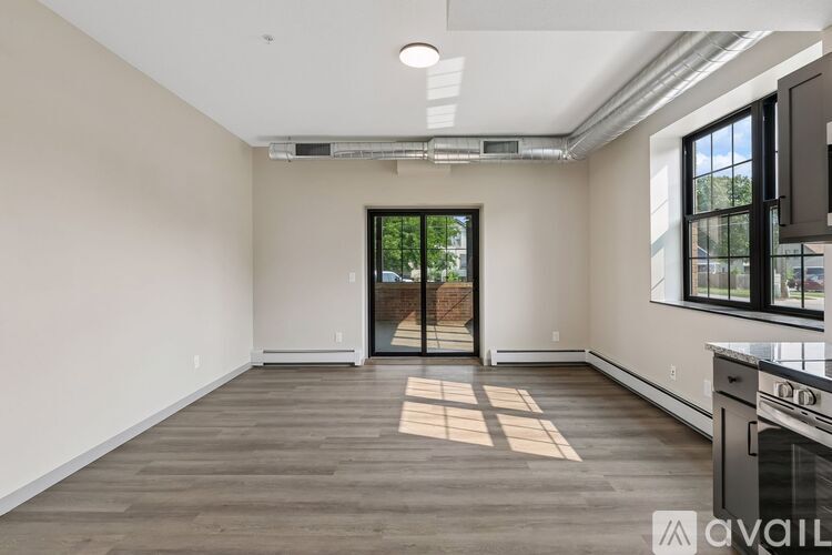 A spacious room with a wooden floor and a sliding glass door leading outside.