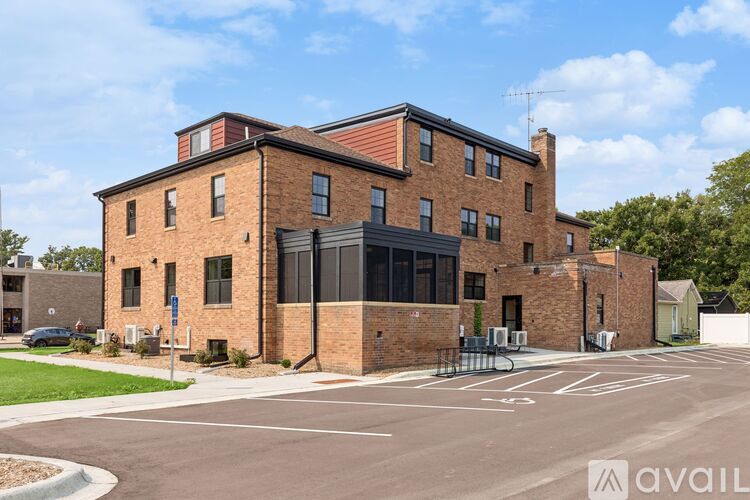 A large brick building with a black awning and a parking lot in front.