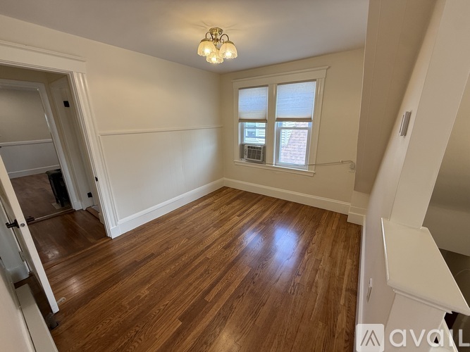 A room with wooden flooring and a window with blinds.