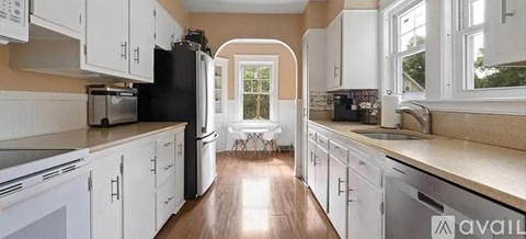 A kitchen with white cabinets and a black refrigerator.