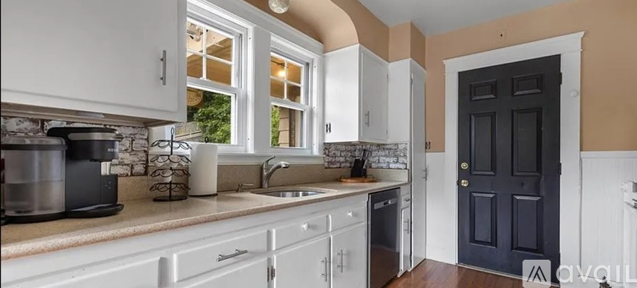 A kitchen with white cabinets and a black door.