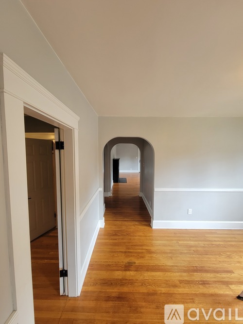 A hallway with a wooden floor and white walls.