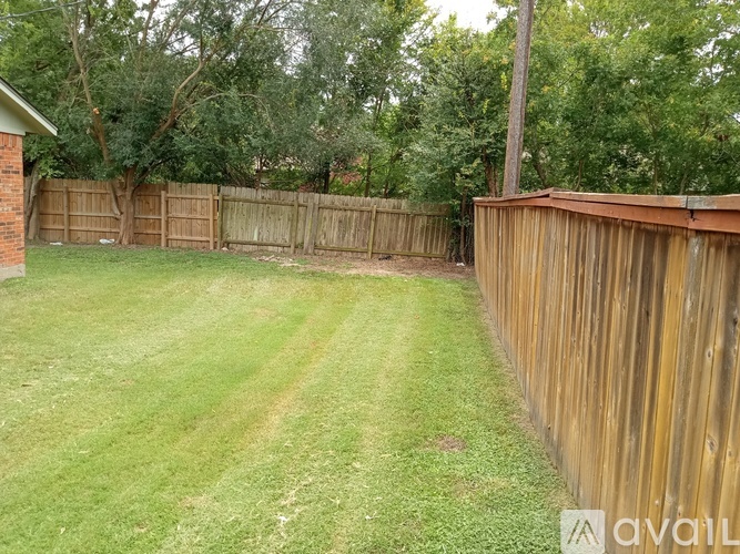 A backyard with a wooden fence and a grassy area.