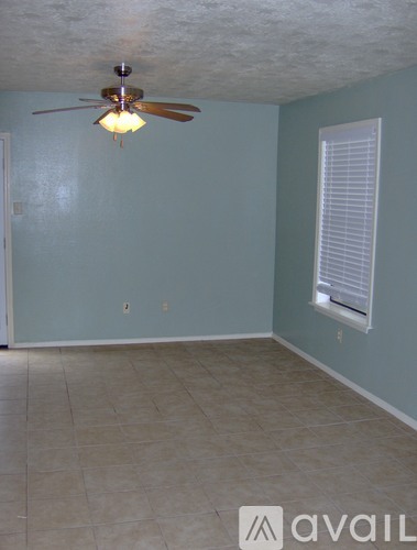 A room with a ceiling fan and a window with blinds.