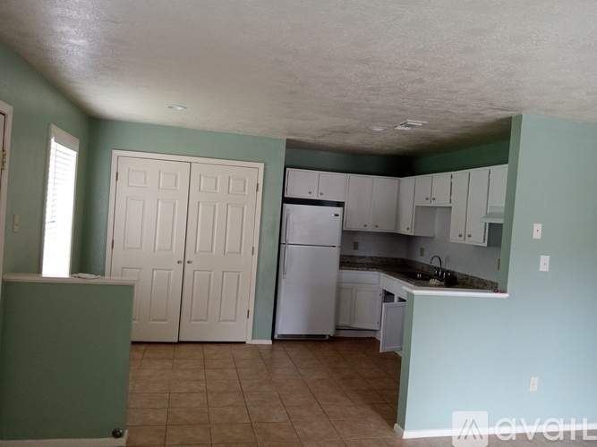 A kitchen with a refrigerator, cabinets, and a counter.