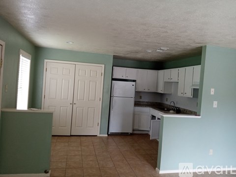 A kitchen with a refrigerator, cabinets, and a counter.