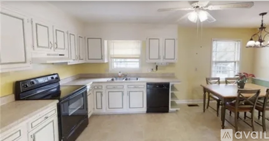 A kitchen with black appliances and white cabinets.
