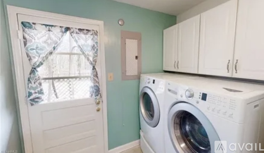 A washing machine sits in a laundry room with a door and a window.