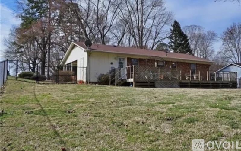 A house with a brown roof is surrounded by a fence and trees.