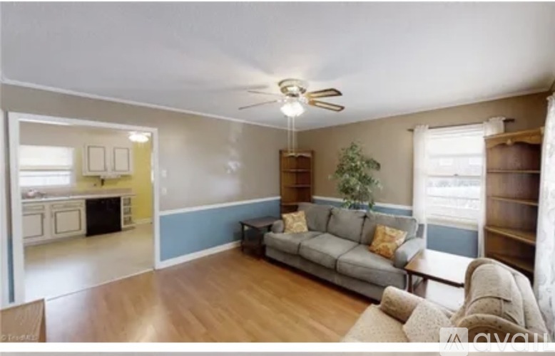 A living room with a grey couch and a ceiling fan.