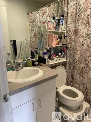 A bathroom with a toilet, sink, and a cabinet with a mirror above it.