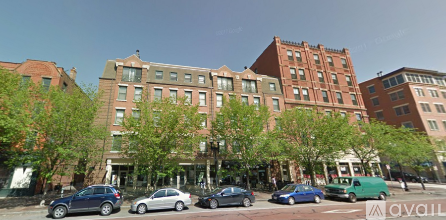 A street view of a row of buildings with cars parked in front.