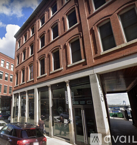 A red car is parked in front of a building with a sign that reads "AVAILABLE".