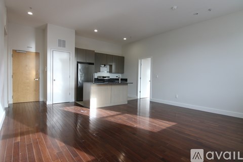 A spacious kitchen with dark wood floors and white walls.