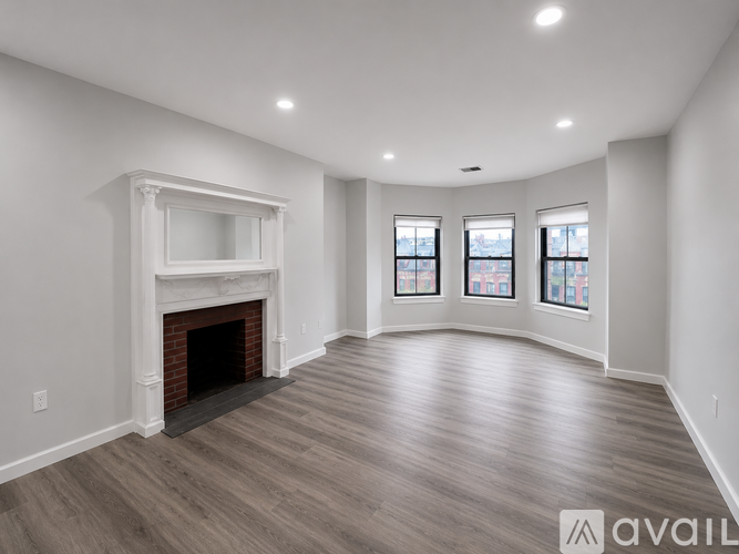 A spacious room with a fireplace and wooden flooring.
