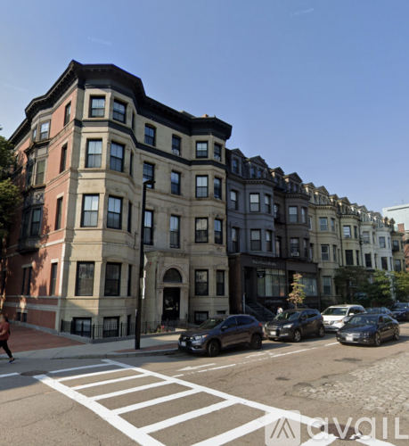 A street view of a row of buildings with cars parked on the side.