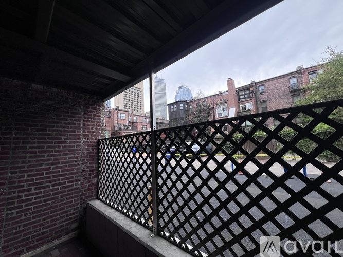 A balcony with a black lattice fence overlooks a cityscape.