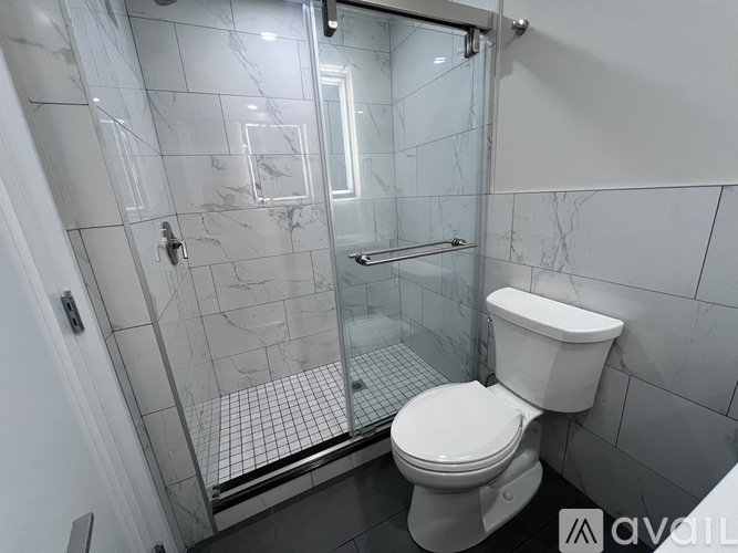 A white toilet in a tiled bathroom with a glass shower door.