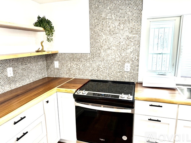 A black oven sits on a wooden countertop in a kitchen.