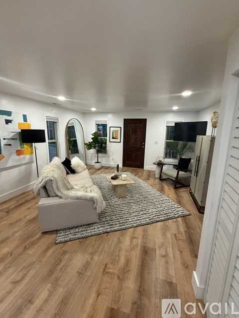 A living room with a grey sofa and a grey rug.