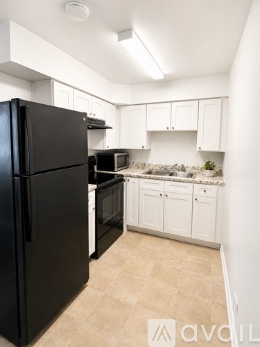 A black refrigerator in a kitchen with white cabinets.