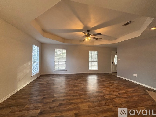 A spacious room with wooden flooring and a ceiling fan.