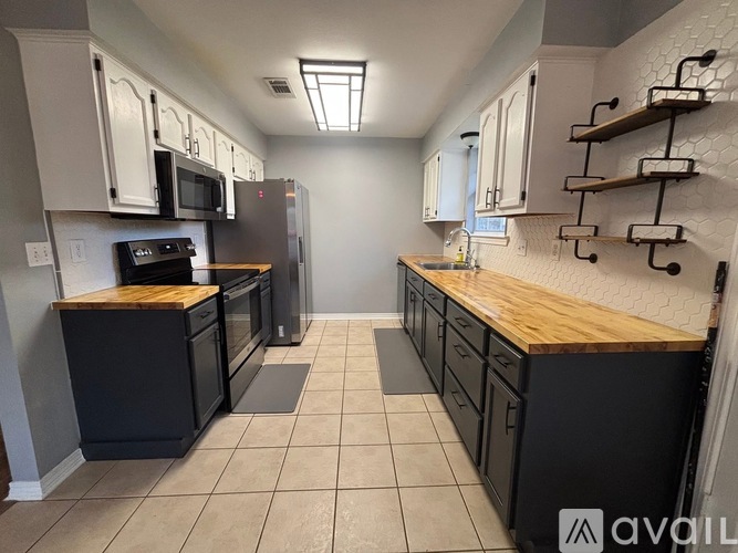 A kitchen with black appliances and wooden countertops.