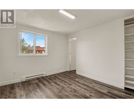 A room with a window showing a view of a house and trees outside.