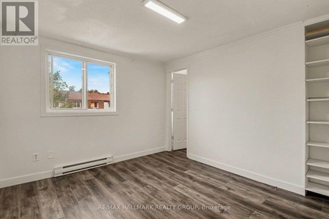 A room with a window showing a view of a house and trees outside.